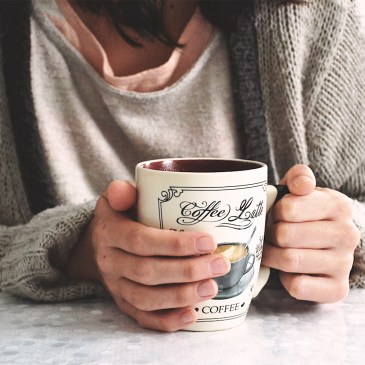 Ragazza che beve caffè in una tazza per colazione